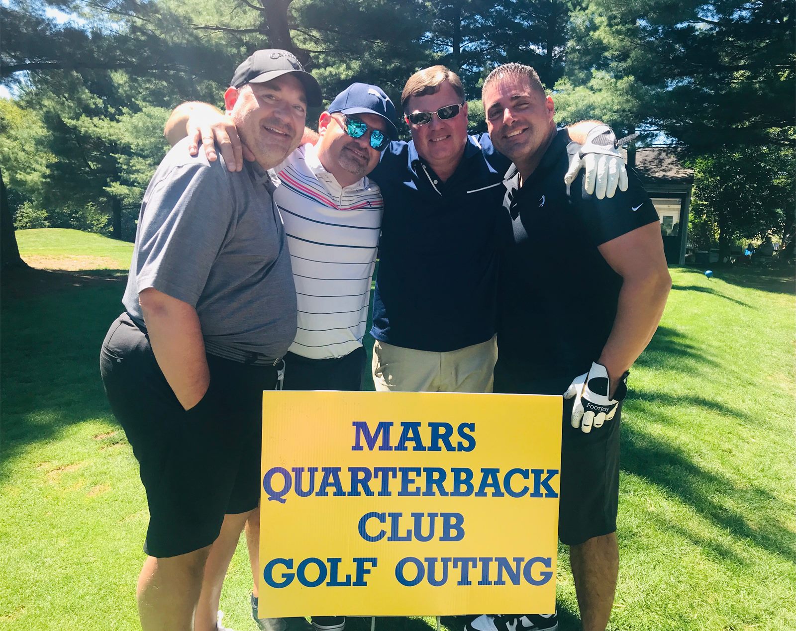 Four golfers holding the Mars Quarterback Club Golf Outing sign