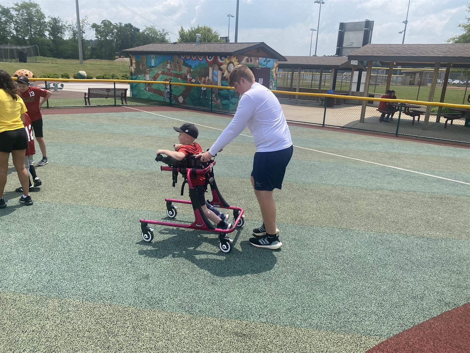 Mars football player helping a Miracle League athlete